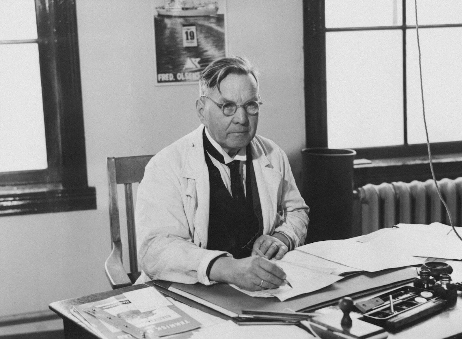 a black and white photo of a man sitting at a desk