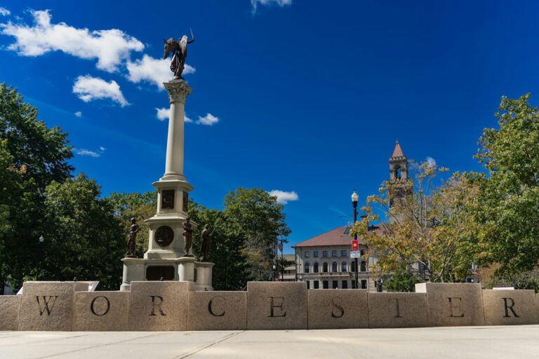 Worcester monument with building and trees under blue sky