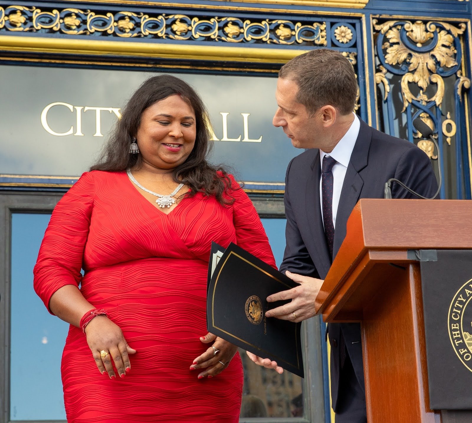   San Francisco Mayor Daniel Lurie hands a signed proclamation of Transgender Immigrants Day to Anjali Rimi on November 18, 2025. Photo by Pax Ahimsa Gethen, CC BY-SA 4.0.  